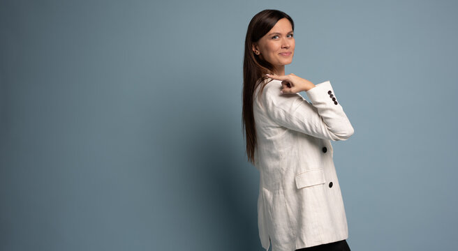 Happy professional business woman looking at camera pointing finger away at copy space, isolated at blue background