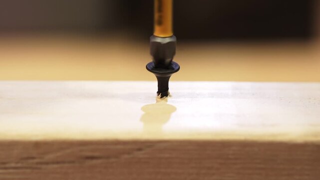 Black Phillips screw being driven into a wooden bar in close-up view