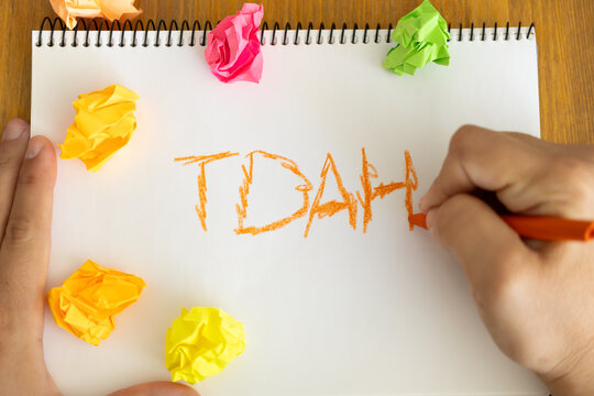 Child writing TDAH in notebook with colorful crumpled paper around