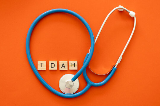 A stethoscope wrapped around the letters that spell TDAH, on an orange background