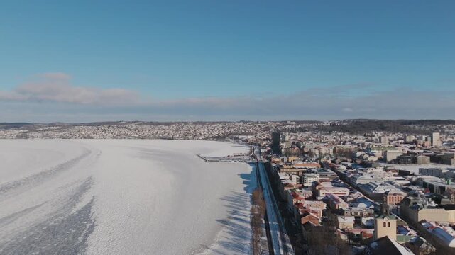 Stunning drone video reveals J&ouml;nk&ouml;ping city center and the vast frozen surface of Lake V&auml;ttern under crisp winter sun, with historic buildings, snowy roofs, and panoramic aerial composition, no people