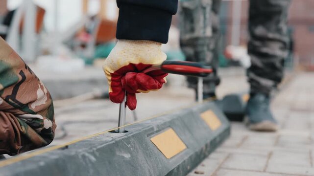 Worker installing rubber parking wheel stop on paved surface close up