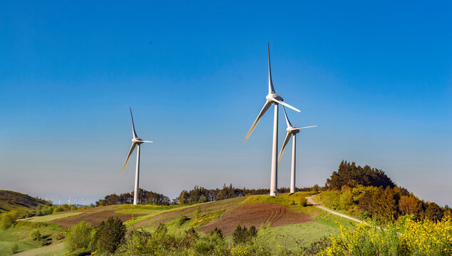 wind turbines  on hill under blue sky in greenery meadow in vaucluse french country