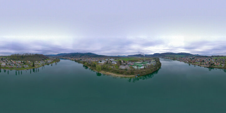 Aerial view of the Rhine River flowing through the town with industrial areas and forested hills under a cloudy sky in Bad Sackingen, Baden-Wurttemberg, Germany.
