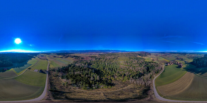 Aerial view of the rural landscape in the Seeland District featuring dense forests and agricultural fields under a clear blue sky Grossaffoltern, Bern, Switzerland.