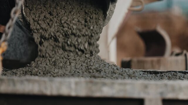 Wet concrete mixture pouring onto construction formwork close up