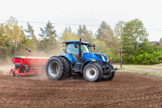 Tractor pulling seed drill machine while sowing field against clear sky