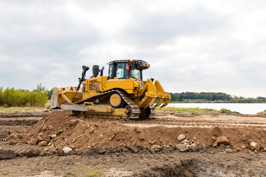 Bulldozer pushing dirt on road against cloudy sky