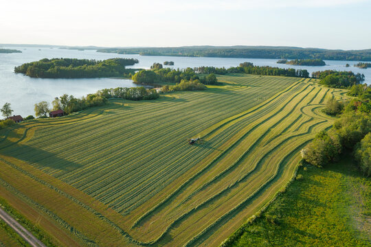 Aerial view of tractor plowing green field against sky
