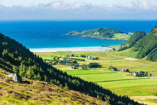 Scenic view of village on lush green landscape near sea against sky