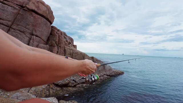 Close View of Young Woman Holding Spinning Rod and Reeling Fishing Line Near Rocky Tropical Shore, Slow Motion Saltwater Fishing and Outdoor Leisure