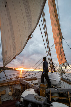 Full length of female sailor looking at sunset while standing on deck of ship during voyage