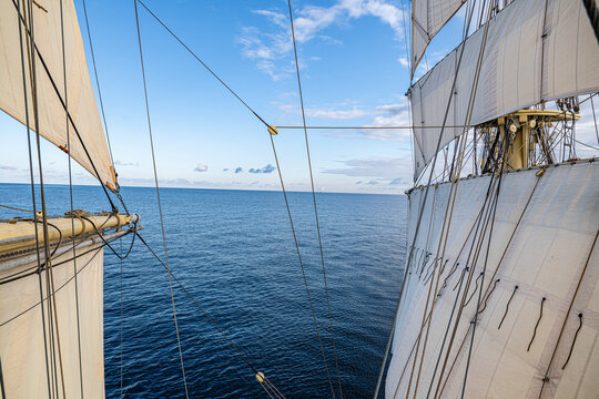 Sails tied with intricate rope rigging on traditional tall ship sailing in sea