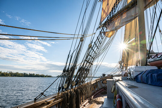 Intricate hemp rigging on tall ship silhouetted against bright sky at sunny day