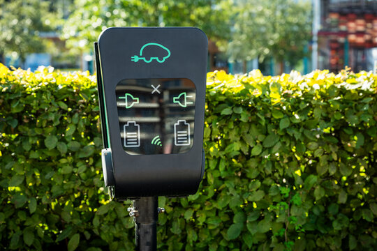 View of electric car charging kiosk against plants