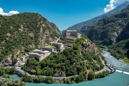 Aerial view of the historic Fort Bard on a rocky hill surrounded by lush green mountains and the Dora Baltea river Bard, Aosta Valley, Italy.