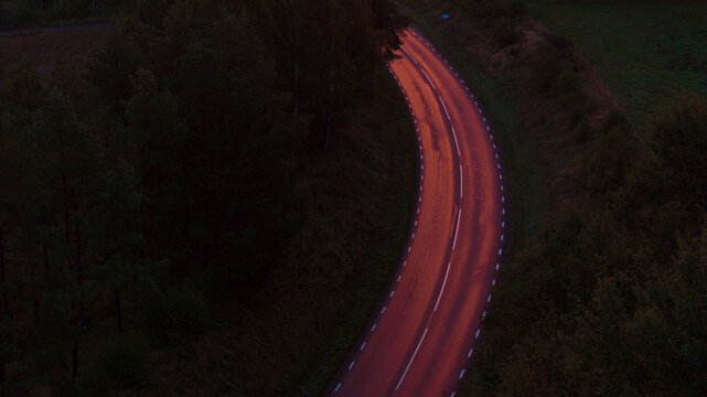 Drone shot of winding road amidst greenery at night