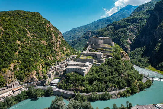 Aerial view of the historic Fortress of Bard perched on a rocky hill above the Dora Baltea river and the surrounding alpine mountains Bard, Aosta Valley, Italy.