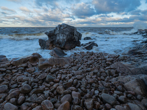 Waves breaking on rocky coast against cloudy sky