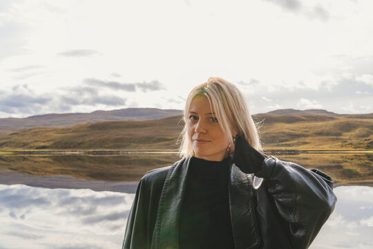 Portrait of blond woman with hand in hair against mountains