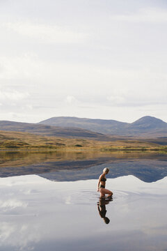 Side view of woman spending leisure time swimming in lake against forest