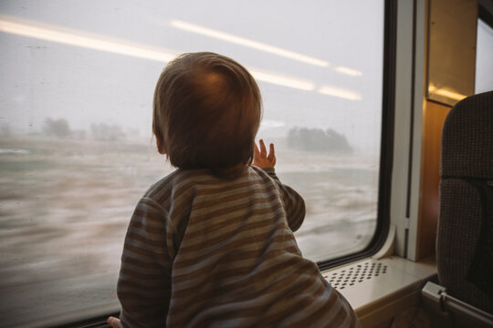 Rear view of boy looking through train window