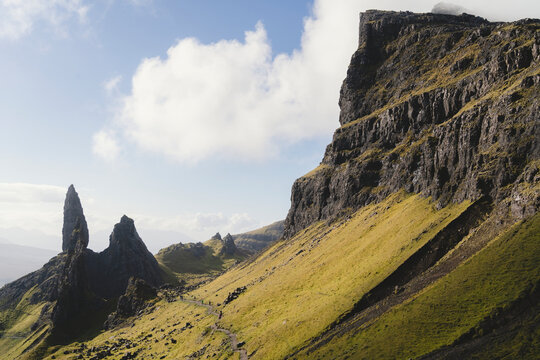 Green slopes with massive rock formations against sky