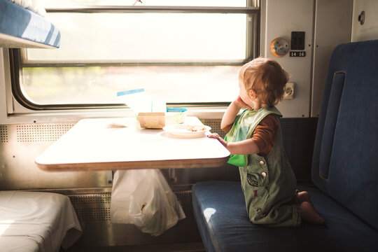 Little boy looking out of window while kneeling on train seat