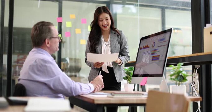 Diverse business colleagues reviewing documents and discussing project details in a modern office setup, fostering teamwork and professional development