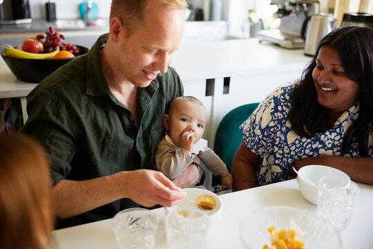 Cute male toddler sitting with father and mother at home