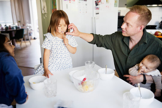 High angle view of girl licking cream while having breakfast with family at home