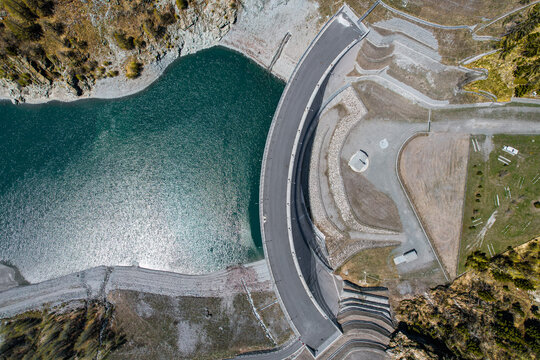 Aerial view of the Beauregard Dam and turquoise reservoir water surrounded by rocky mountain slopes in Valgrisenche, Aosta Valley, Italy.