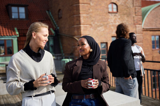Smiling multiracial businesswomen on office terrace during coffee break