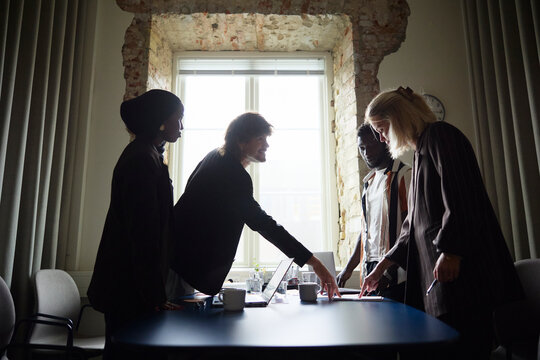 Group of diverse entrepreneurs planning business strategies while standing around table at office