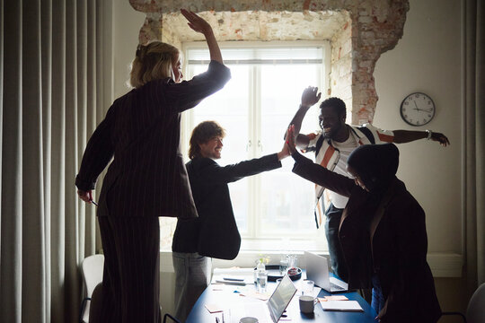 Happy male and female business professionals giving high-five to each other at workplace