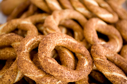 Close-up of traditional Turkish simit pastry covered with toasted sesame seeds. Macro shot of crispy golden bagels pile, street food culture, authentic bakery products, and traditional breakfast