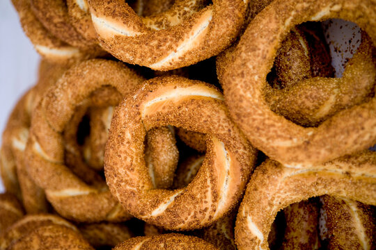 Close-up of traditional Turkish simit pastry covered with toasted sesame seeds. Macro shot of crispy golden bagels pile, street food culture, authentic bakery products, and traditional breakfast