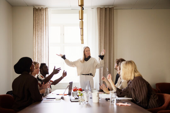 Female entrepreneur gesturing while talking with coworkers in office meeting