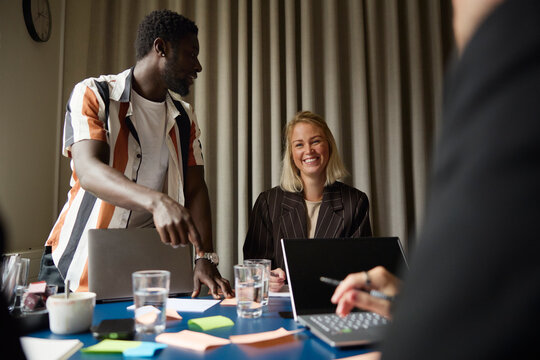 Smiling businesswoman interacting with coworkers during brainstorming session at office