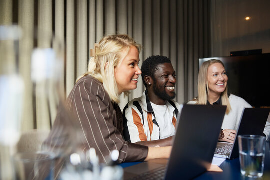 Smiling male entrepreneur sitting with female colleagues in meeting at office