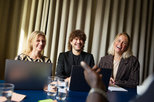 Group of happy entrepreneurs sitting together in office board room