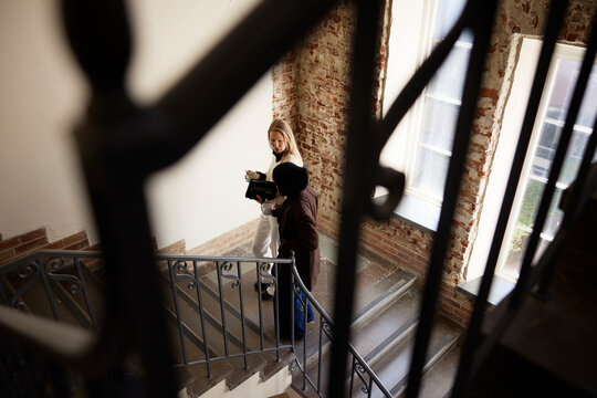 High angle view of multiracial businesswomen moving up on stairs seen through railing