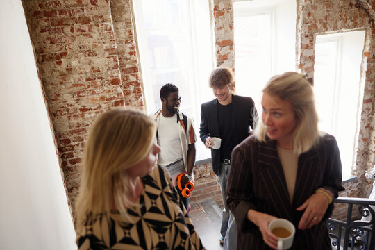 Group of business professionals talking while moving up on stairs during coffee break