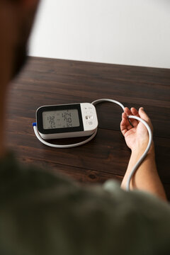 Over the shoulder view of measurements seen on gauge while man checking his blood pressure at home