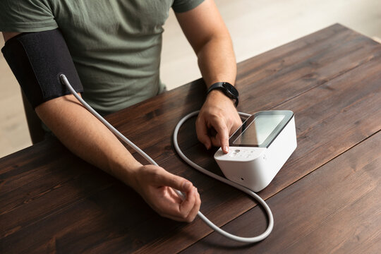 High angle view of man using gauge while checking blood pressure at home