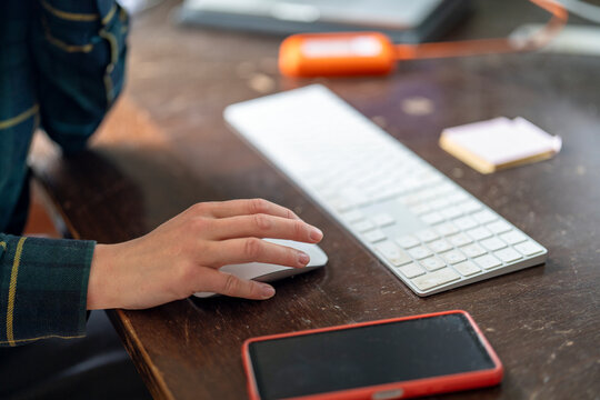 Hand of freelancer on computer mouse at desk in home office