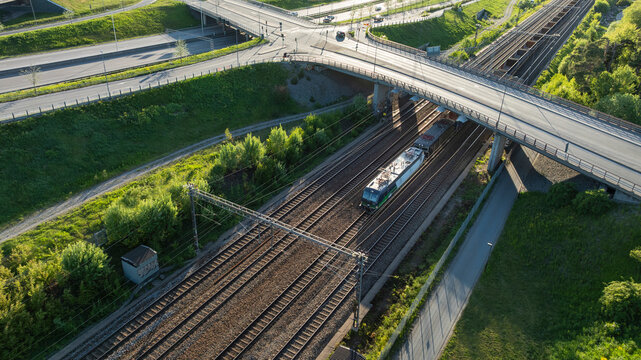 Drone view of train passing under bridge on sunny day