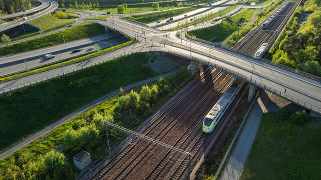 Drone view of passenger train passing under bridge on sunny day