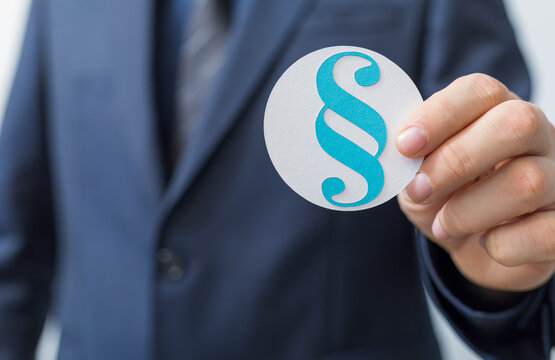 Businessman holding a paragraph symbol in a white circle. Concept of law, justice, or business.