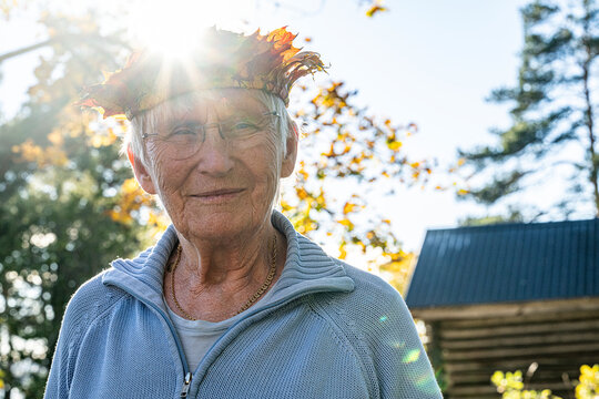 Portrait of smiling senior woman wearing eyeglasses and crown at sunny day